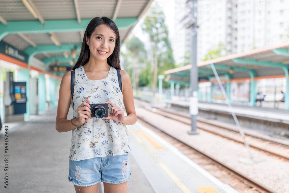 Young asian Woman holding digital camera in light rail station