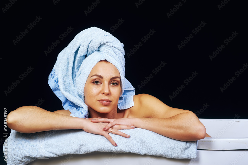Young beautiful woman with towel on head nourishes the skin on a dark background. Beauty treatments . Young beautiful woman with towel on head nourishes the skin on a dark background. Beauty treatments .