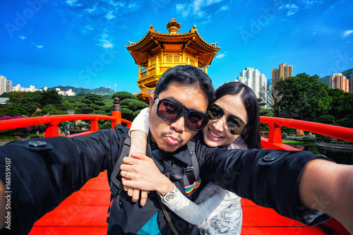 Photography Young couple taking selfie with Gold Chinese pavilion Temple at the park in Hong