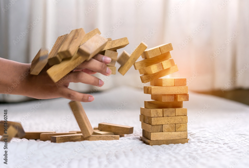 Young man pulling out wood block fail on building tower at home and drape change, choice business risking dangerous project plan failure construction