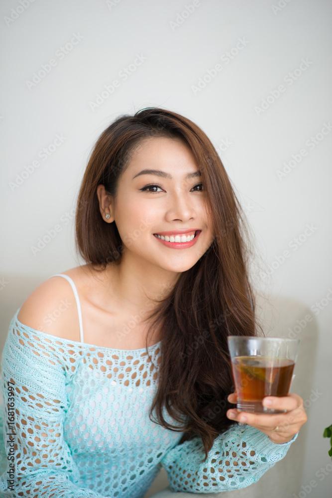 Beautiful young asian woman drinking her morning tea over a breakfast at home. Beautiful young asian woman drinking her morning tea over a breakfast at home.