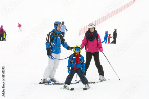 Young happy family with one child, skiing in the mountains