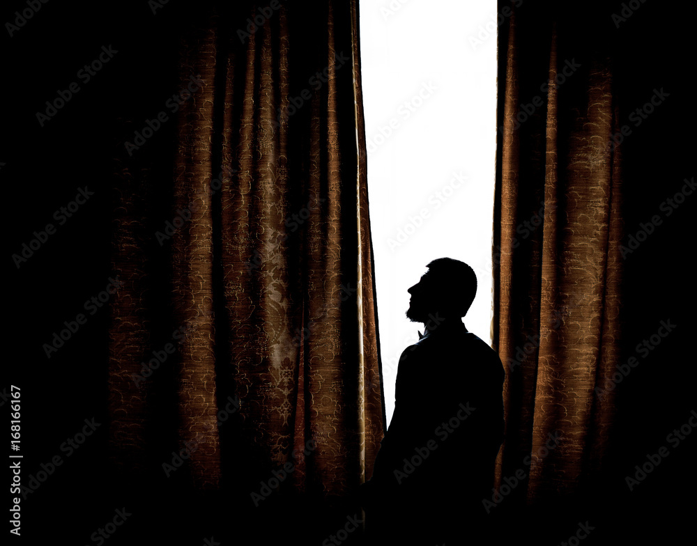Silhouette of a man standing before a bright window