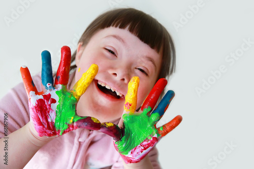 Cute little down syndrome girl with painted hands.
