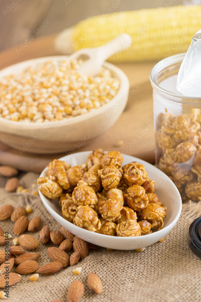 Corn kernels in wooden plates and popcorn with Caramel and almond cream on wooden table Corn kernels in wooden plates and popcorn with Caramel and almond cream on wooden table