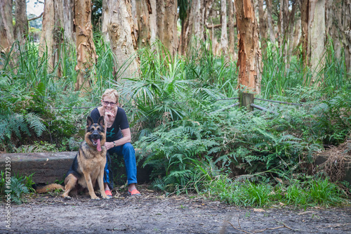 Photography A woman and german shepherd dog in a forest of paperbark trees