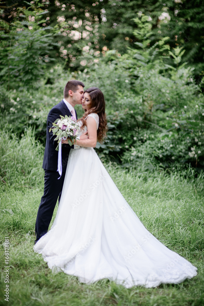 Beautiful wedding couple poses in a green garden