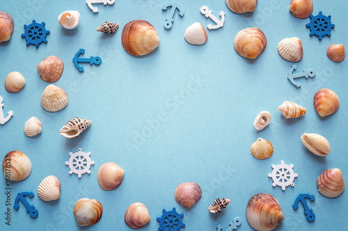 Frame of shells, decorative anchors and steering wheels on a blue background. Top view with copy space.