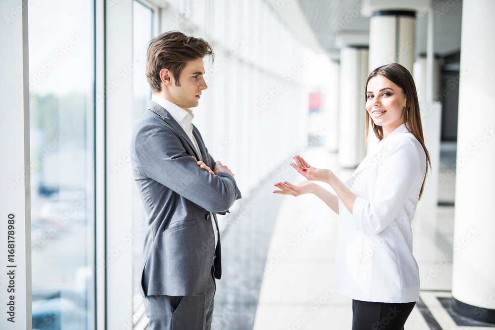Business men and women talking with a smile on the background of the large panoramic windows in a modern business center. Models dressed in a dark business suits. Business men and women talking with a smile on the background of the large panoramic windows in a modern business center. Models dressed in a dark business suits.
