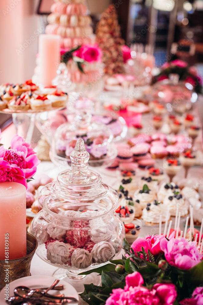 Dishes with tasty cookies with pink icing and berries stand on the candy bar