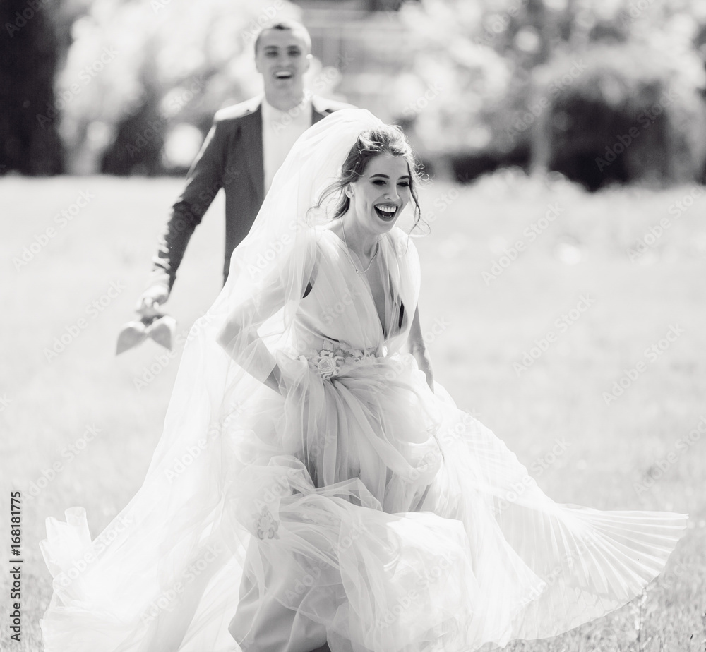 Stunning bride runs from groom on the green lawn Stunning bride runs from groom on the green lawn