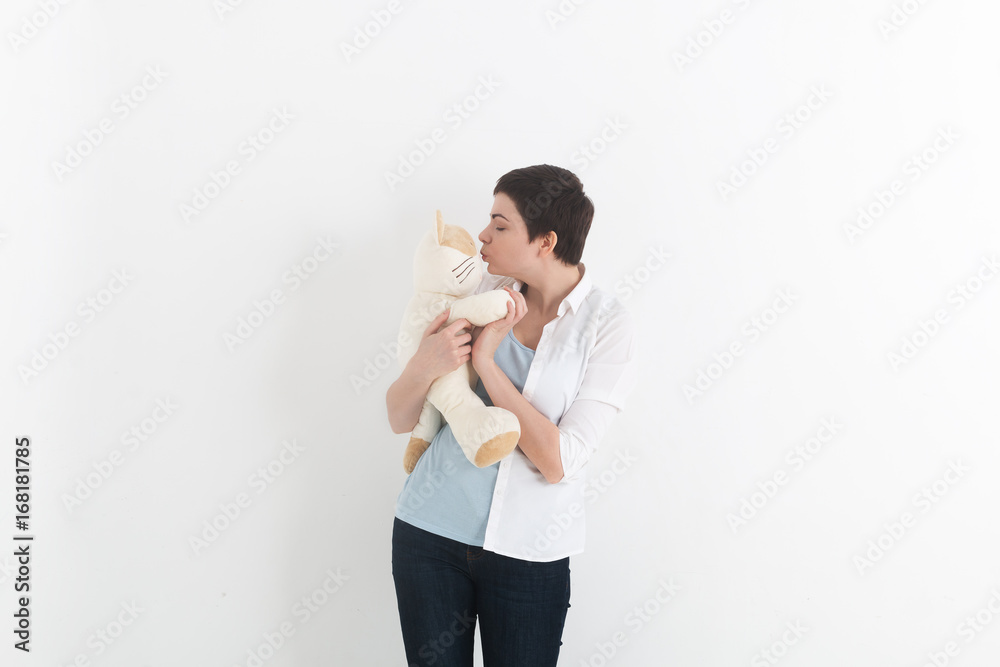 Woman standing and kissing her white and lovely plush cat. Woman standing and kissing her white and lovely plush cat.