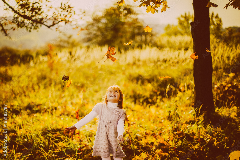 Girl plays with fallen leaves in the evening
