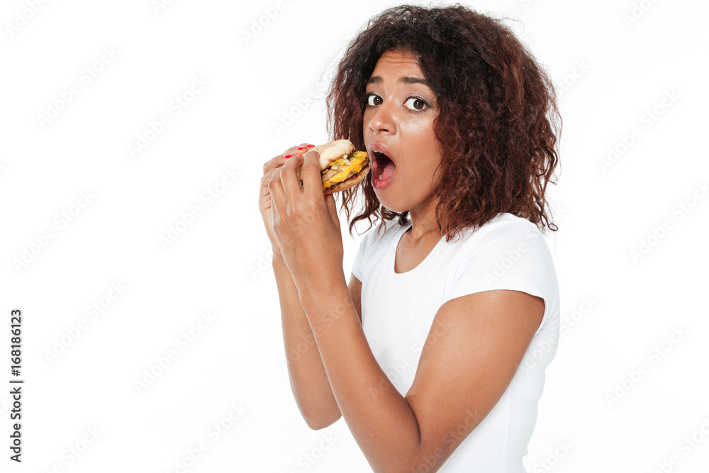 Confused young african woman eating burger. Confused young african woman eating burger.