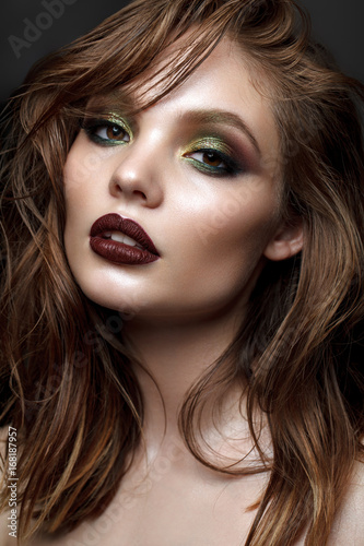 Beautiful young model with evening makeup and wavy hairstyle. Green smoky eyes and wine lips. trendy hairstyle