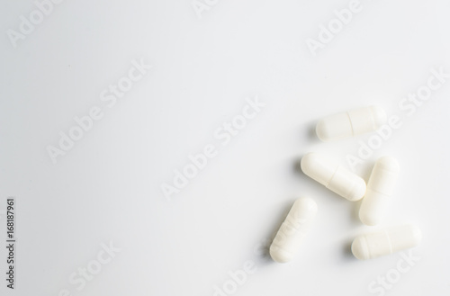 White capsule pills on white background