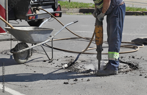 Asphalt demolishing, worker using jackhammer to brake pavement  © sima