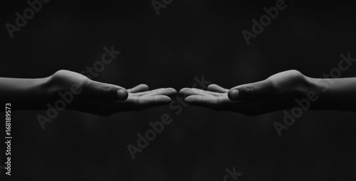 A panoramic black and white close up of hands almost touching