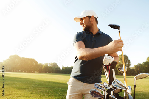 Man golfer taking out the golf club from a bag photo