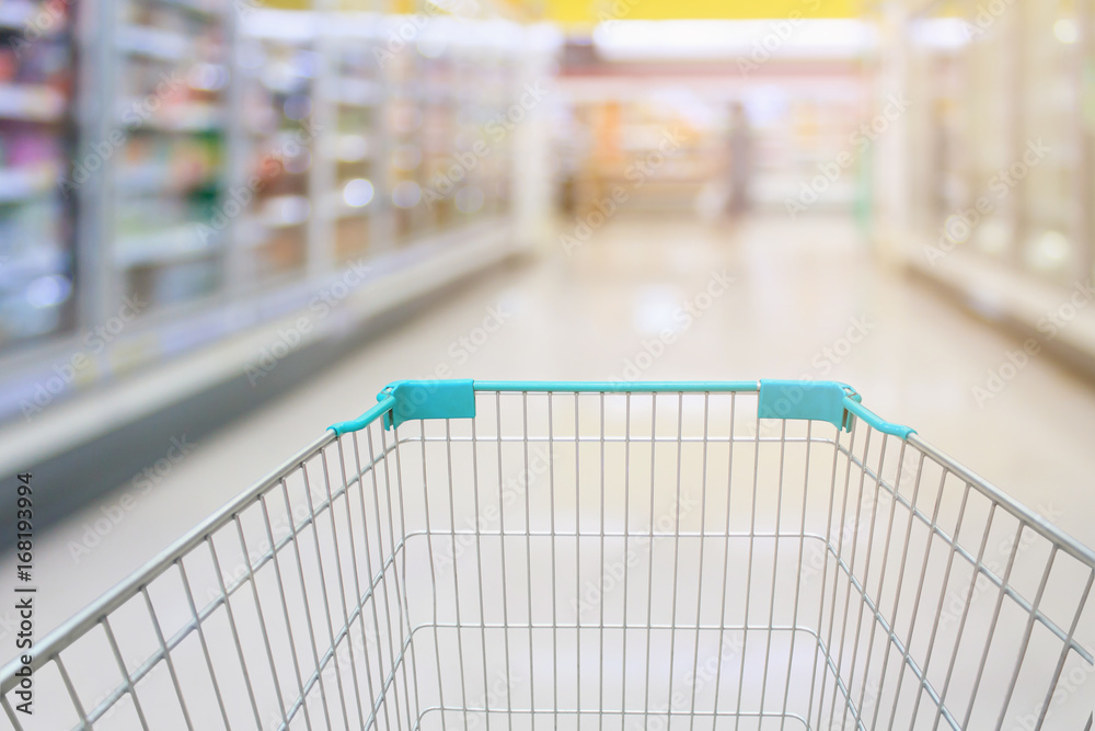 Shopping cart view with milk and yogurt product shelves aisle in supermarket
