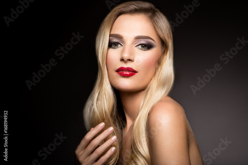 Beautiful blonde model girl with long curly hair . Hairstyle wavy curls . Red lips . Fashion   beauty and make up portrait