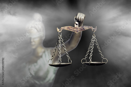 Lady Justice or Themis (God of Justice) raising the Scale of justice through fog (Concept of hope in justice)