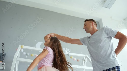 Positive father and little daughter dancing at home