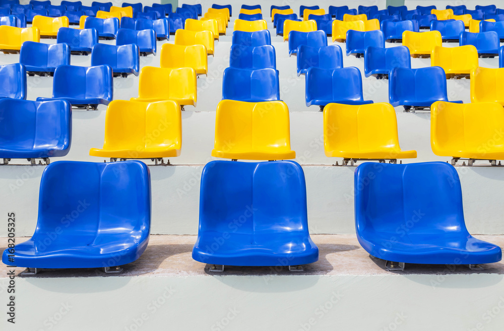 Obraz premium Rows of empty blue and yellow plastic seats in public sport stadium