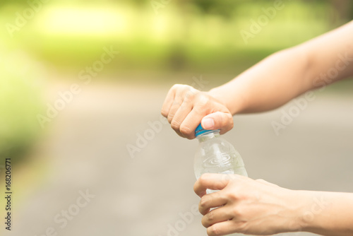 Woman hand open water bottle cap in the green garden