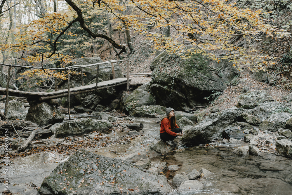 Caucasian woman sitting on rock in stream