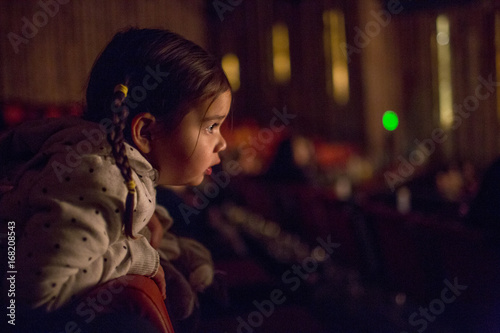 Mixed Race girl leaning on chair watching movie in theater photo