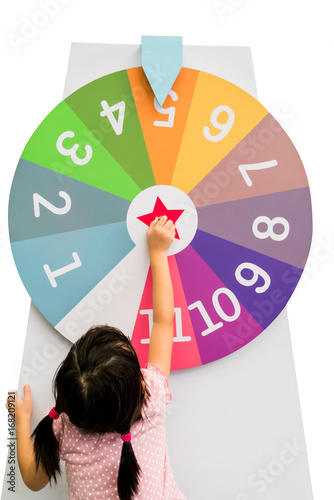 Asian girl trying to spin the huge colorful fortune wheel with white digit numbers