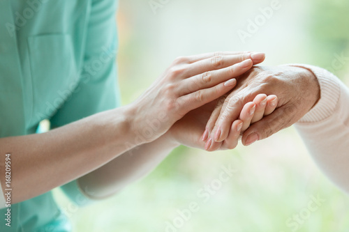 Caretaker massaging pensioner's hand photo