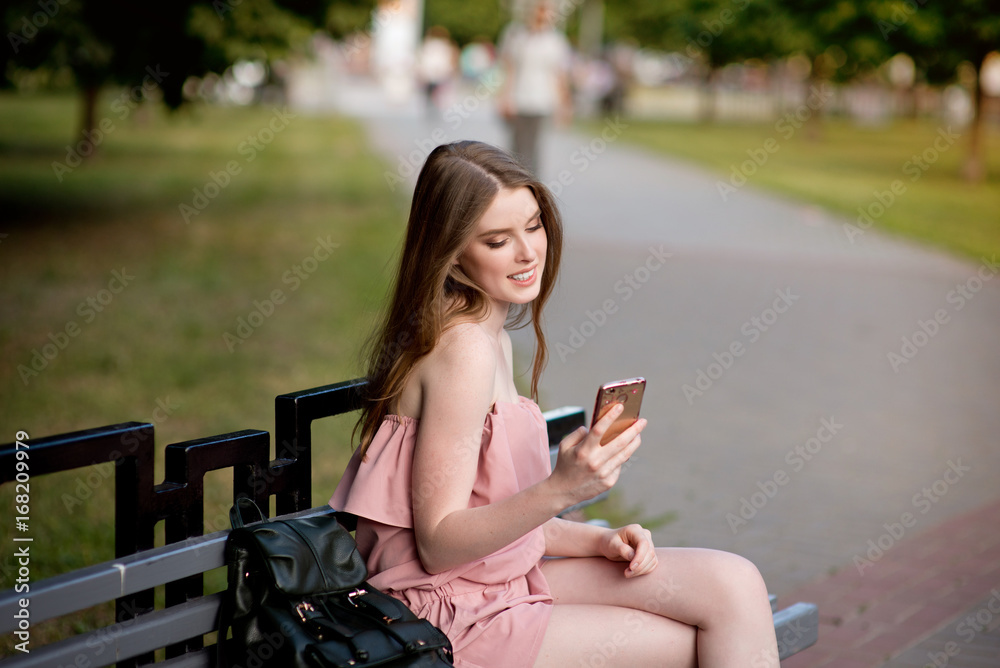 Young beautiful stylishly dressed girl with beautiful hair is walking along the streets of the city at sunset, in sunny rays Young beautiful stylishly dressed girl with beautiful hair is walking along the streets of the city at sunset, in sunny rays