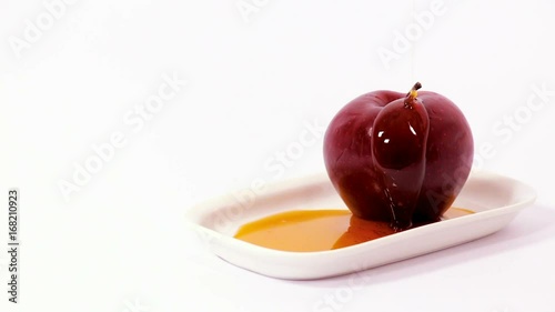 Cinemagraph of pouring honey on red apple on white plate