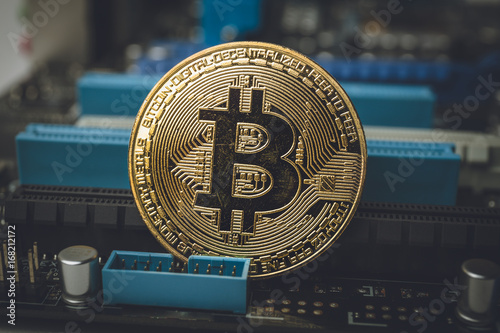 Golden Bitcoin coin among computer microschemes, internet money concept photo
