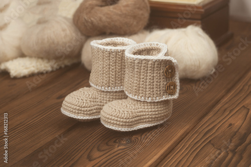 baby winter knitted booties on wooden background