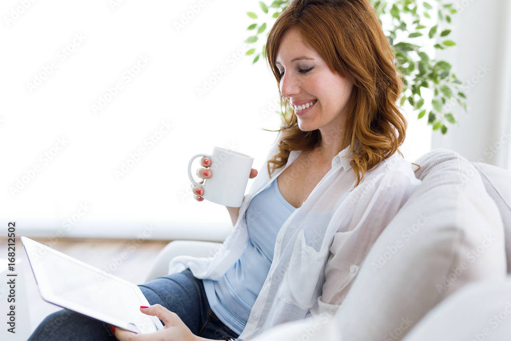 Beautiful young woman using her digital tablet at home. Beautiful young woman using her digital tablet at home.
