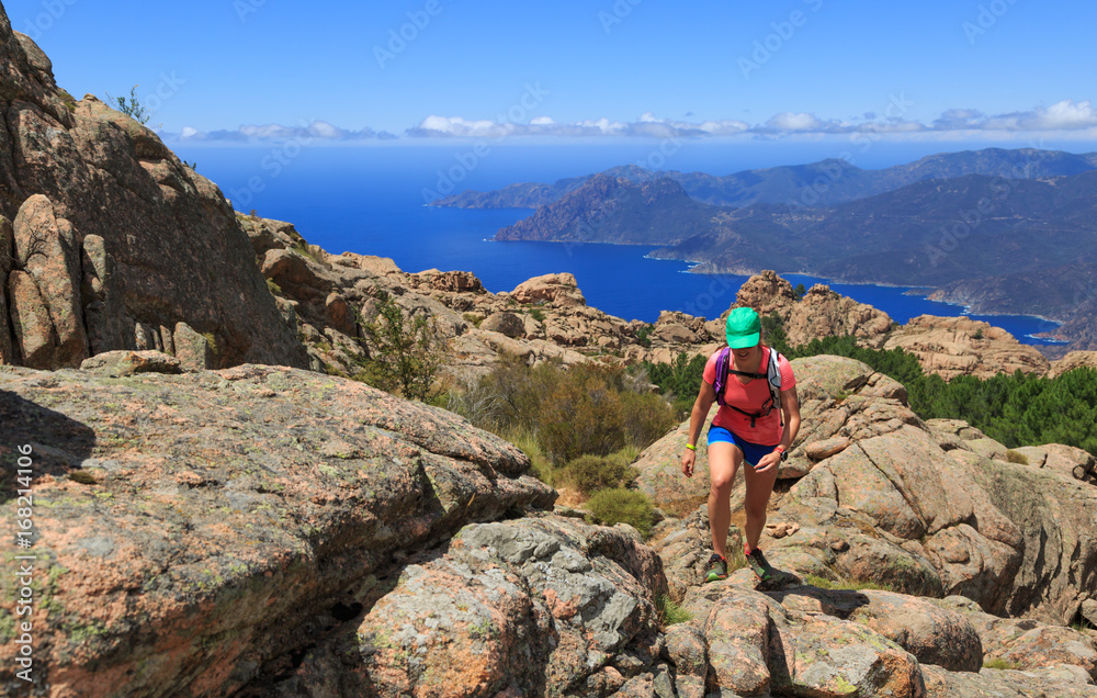 Woman hiking on a trail in the mountains of Corsica, France.