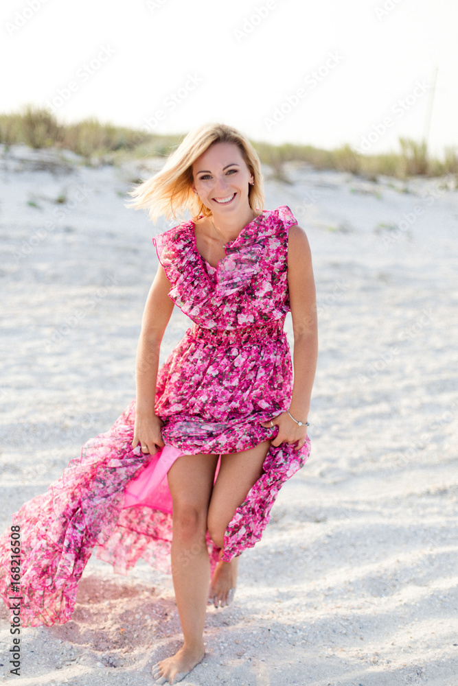 Happy smiling woman in beautiful dress running and dancing on the beach. Concept of vacation and leisure. Happy smiling woman in beautiful dress running and dancing on the beach. Concept of vacation and leisure.
