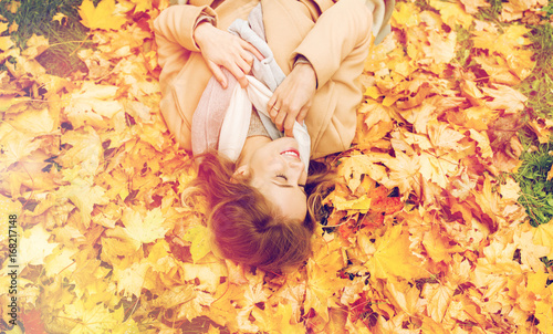 beautiful happy woman lying on autumn leaves