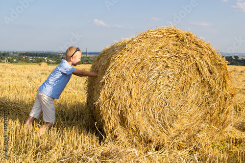 Boy pushes a bale of hay