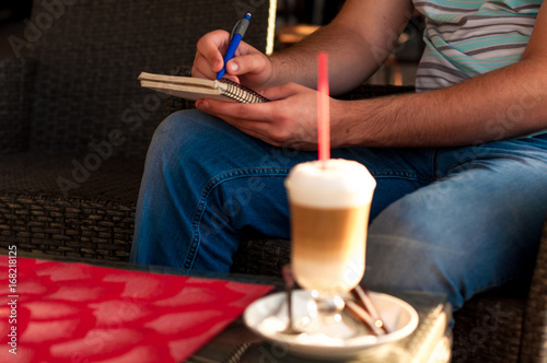 Man leafs through the diary and drinking coffee latte