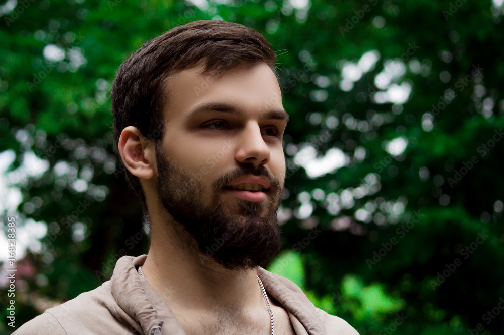 Close-up Portrait of young man with a beard smiling. outside in the park Close-up Portrait of young man with a beard smiling. outside in the park