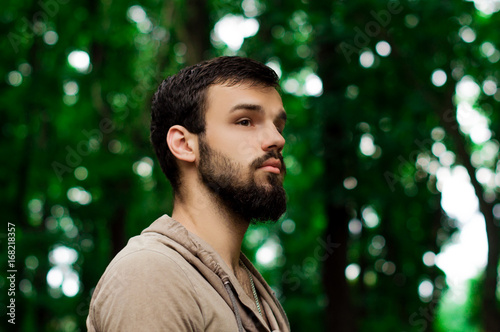 young bearded hipster man. facial profile. outside in the park