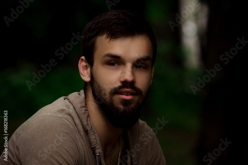Close-up Portrait of young man with a beard smiling. outside in the park photo