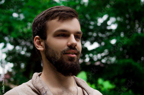 Close-up Portrait of young man with a beard smiling. outside in the park