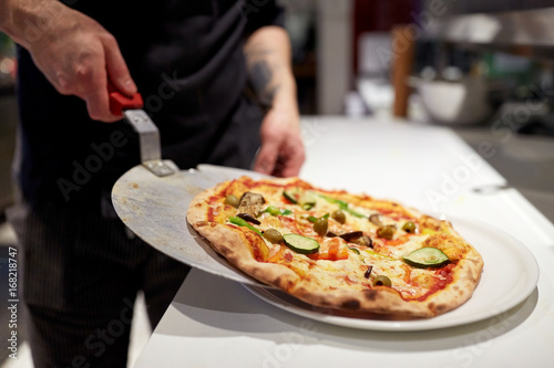 cook with baked pizza on peel at pizzeria photo