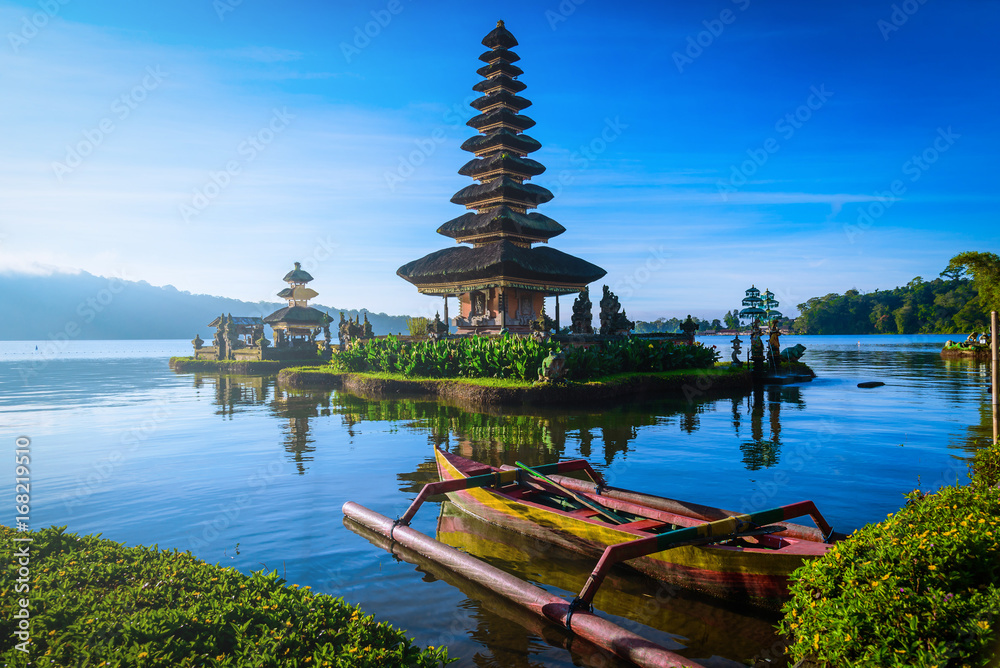 Fototapeta premium Pura Ulun Danu Bratan, Hinduska świątynia z łodzią na Bratan jeziora krajobrazie przy wschodem słońca w Bali, Indonezja.