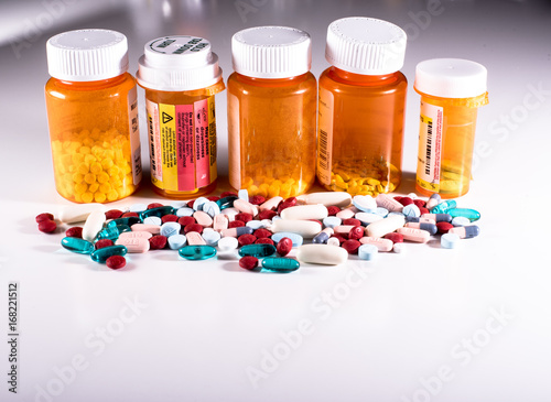 Five pill bottles with pile of pills